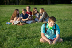 lonely teenager sitting away from group